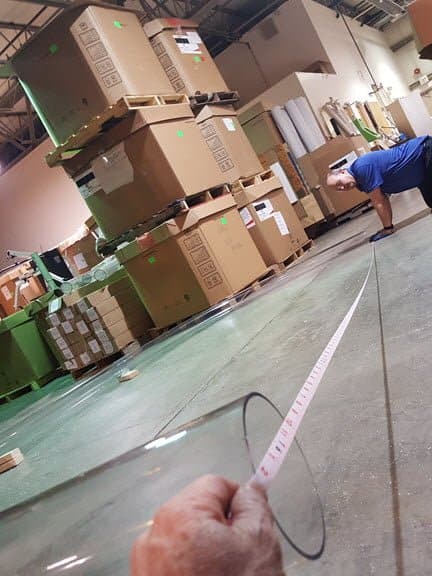 Employees measuring the distance between the two ends of the long tubing bend