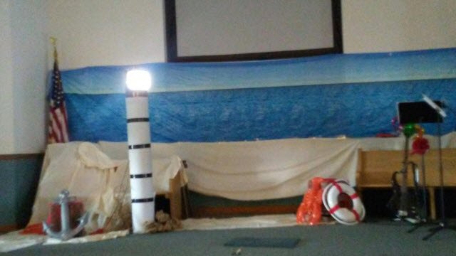 The finished lighthouse model lit up at the front of a church