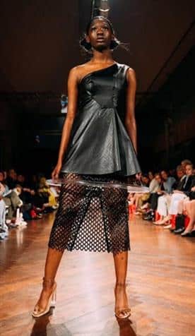 A model wearing the black hoop circle dress with a circle of tubing hanging from the hem of the dress
