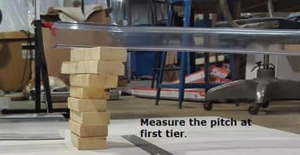 Rectangular tubing set on wooden blocks. Caption says, "measure the pitch at first tier."