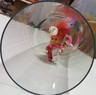 Looking down the barrel of a clear tube with troll dolls inside