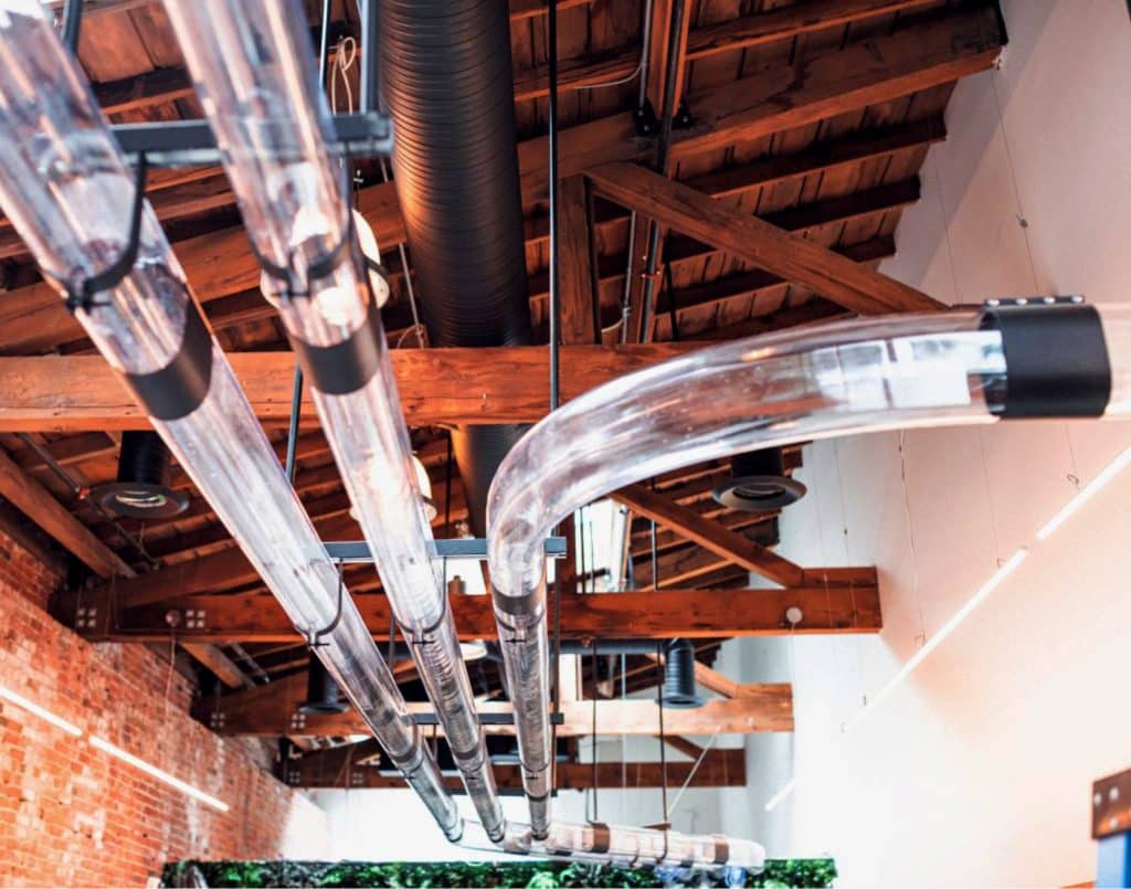 Pneumatic tritan tubing conveying system in a bright room with wooden ceiling and rafters