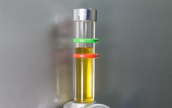 A clear tubing sight glass with oil levels between red and green markers