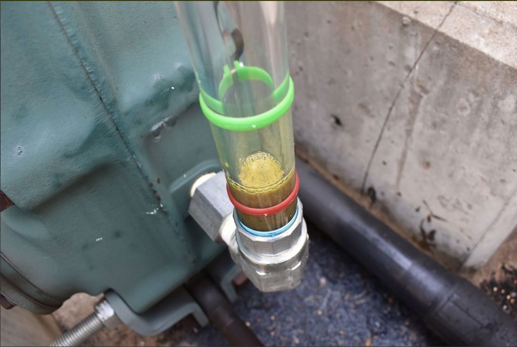 A sight glass made from plastic tubing showing the oil level of machinery