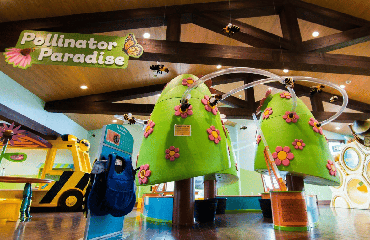 The honey been exhibit in a children's museum featuring large plastic trees with tubing spirals running through them.
